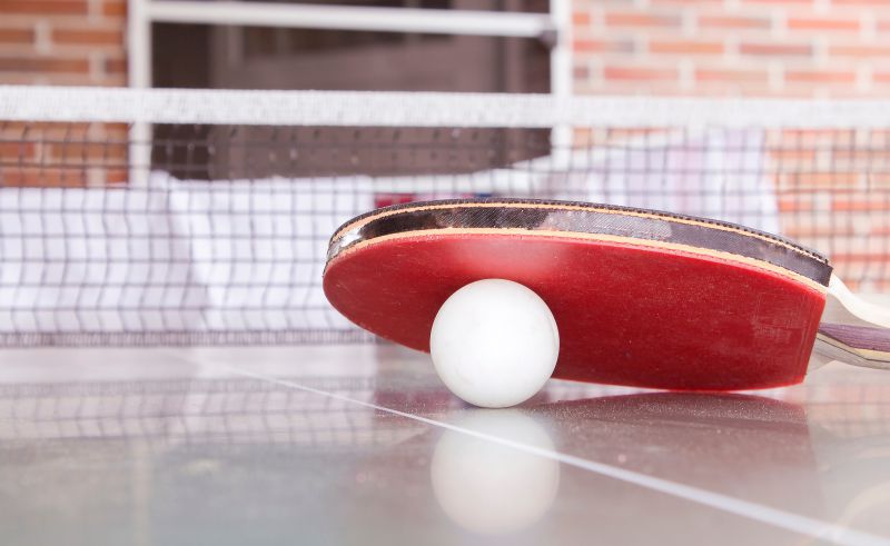 Schlaeger und Ball auf einer Outdoor Tischtennisplatte Tischtennisplatte Schlaeger Ball draussen