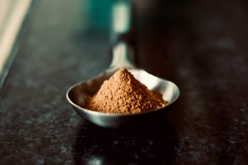 Braunes Proteinpulver auf Löffel Proteinpulver auf einem kleinen Löffel