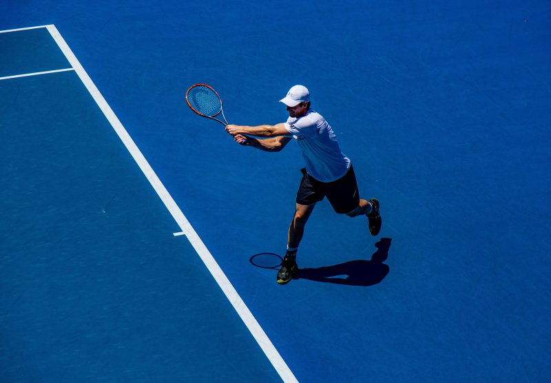 Mann hält einen Tennisschläger auf einem blauen Feld