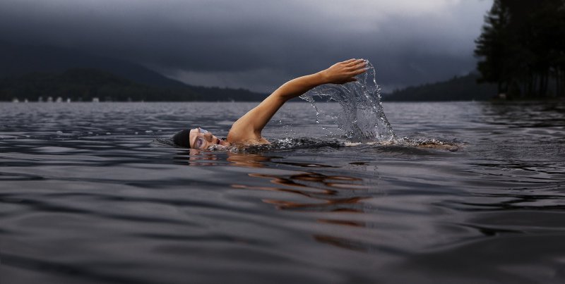 Im See mit Sportkopfhörern schwimmen
