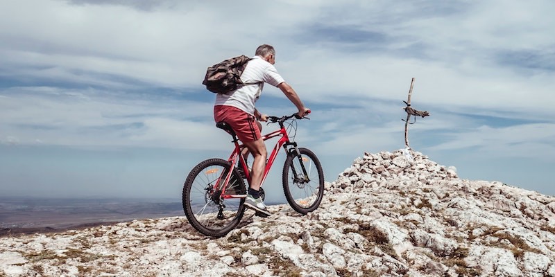 Fahrradfahrer mit seinem Mountainbike auf Felsen Fahrradtypen Kaufkriterien