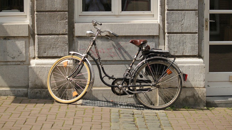 Ein klassisches Hollandrad das an einer Wand abgestellt ist. Hollandrad