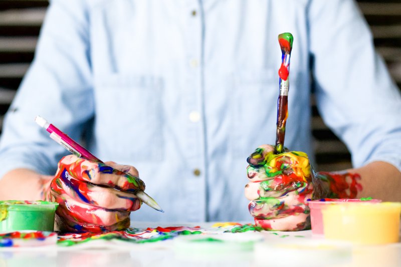 Malen mit Pinsel und Acrylfarben auf Stoff. Acrylfarben besitzen eine unterschiedliche Viskosität, die von flüssig bis pastos reicht.