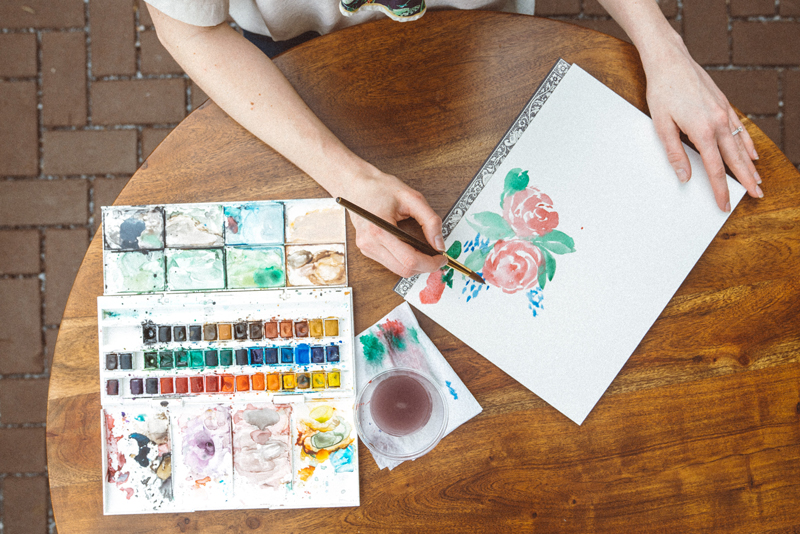 Frau malt ein Aquarellbild mit Blumen Aquarellblumen malen