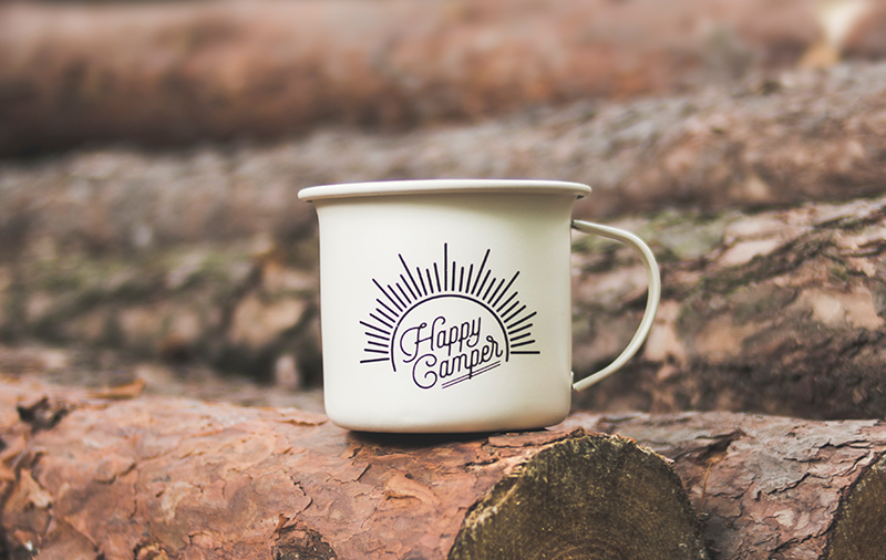 Eine "Happy Camper" Metall-Tasse auf Holzstämmen Camping-Tasse auf Holz