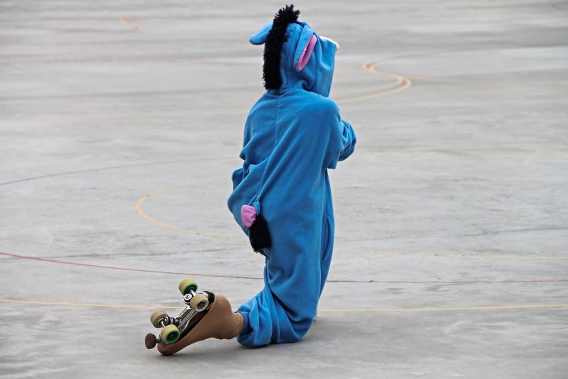 Ein Rollschuhfahrer im I-Ah Kostüm auf Rollkunstaufschuhen in einer Skate-Halle Skating, Rollkunstlauf in Rollkunstlauf-Rollschuhen