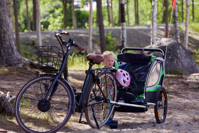 Das Kind im Fahrradanhänger mit dem Kinderfahrradhelm Das Kind im Fahrradanhänger mit dem Kinderfahrradhelm