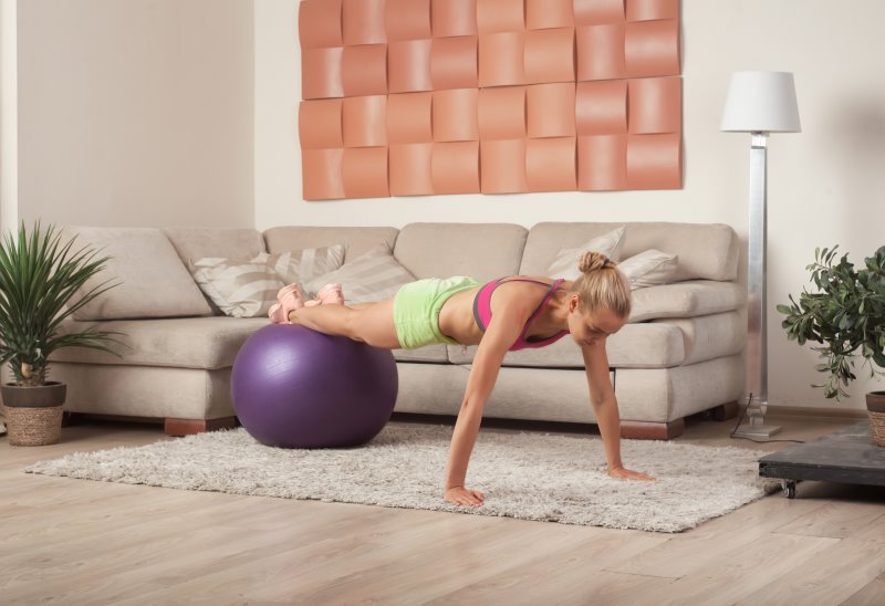 Frau macht ein Homeworkout mit einem Gymnastikball Workout mit dem Gymnastikball als Alternative zum Balancekissen