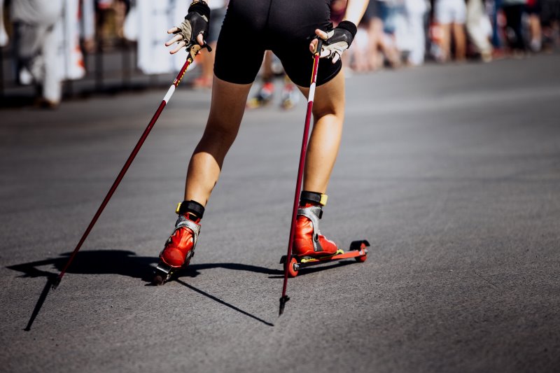 Skiroller-Fahrer in der Skating-Technik mit Stöcken und Schuhen im Fokus