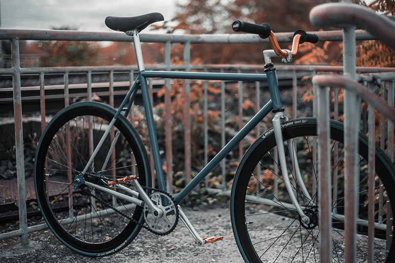 türkises SingleSpeed-Bike steht zwischen Geländergittern