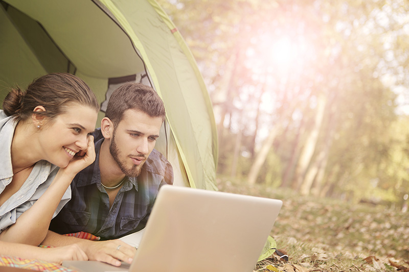 Zwei Personen die im Zelt liegend auf einen Laptop schauen