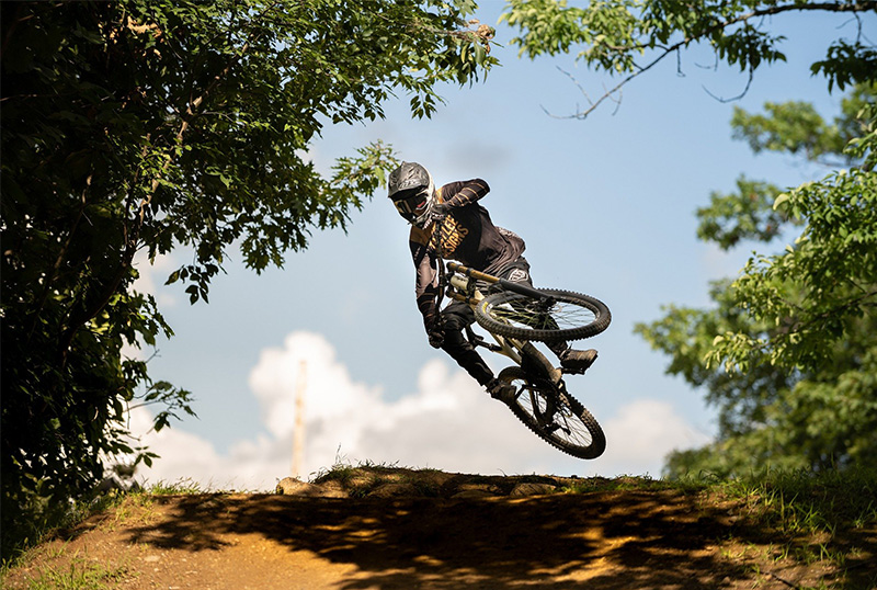 Der so genannte "Whip", den der Biker hier macht, solltest Du erst mit genügend Bike Erfahrung ausprobieren. Ein Downhill Biker hebt mit seinem Bike ab.