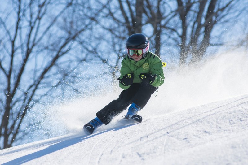 Kind fährt schnell die Piste hinunter Kind fährt die Piste hinunter