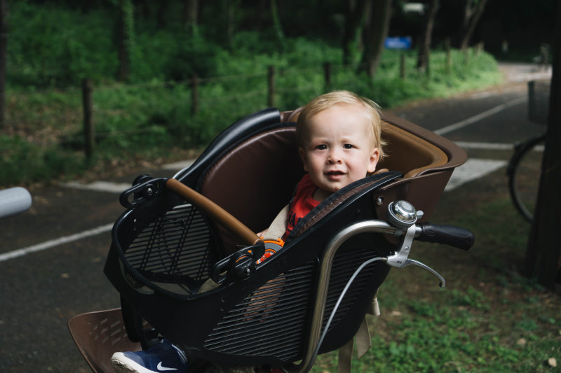 Kind in einem Kinderfahrradsitz für vorne Kind in einem Kinderfahrradsitz für vorne