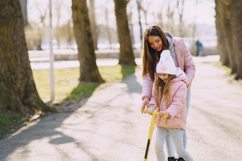 Familienspaß Mutter hilft Kind beim Fahren