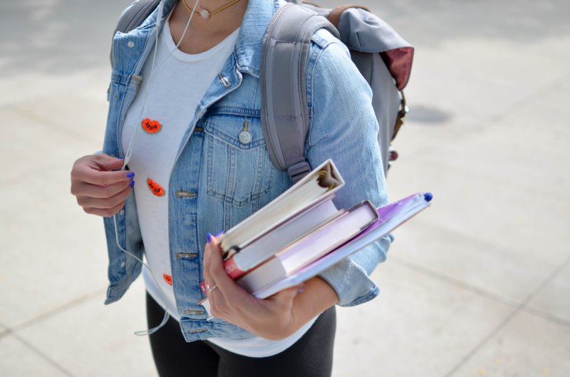 Studentin mit Büchern in der Hand und Rolltop Rucksack Studentin mit Büchern und Rolltop Rucksack