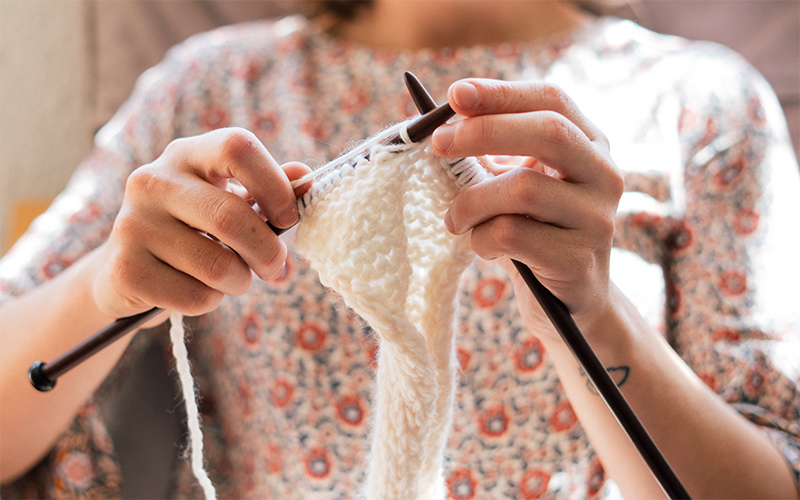 Eine Frau, die mit Stricknadeln strickt