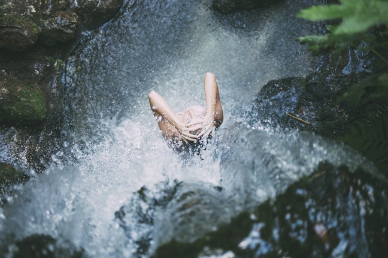 Eine Frau duscht in einem Wasserfall
