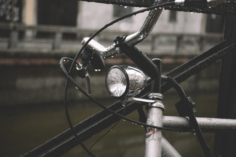 Fahrradbeleuchtung mit Fahrraddynamo im Regen Die Vorderseite eines Fahrrades. Es ist nass vom Regen.