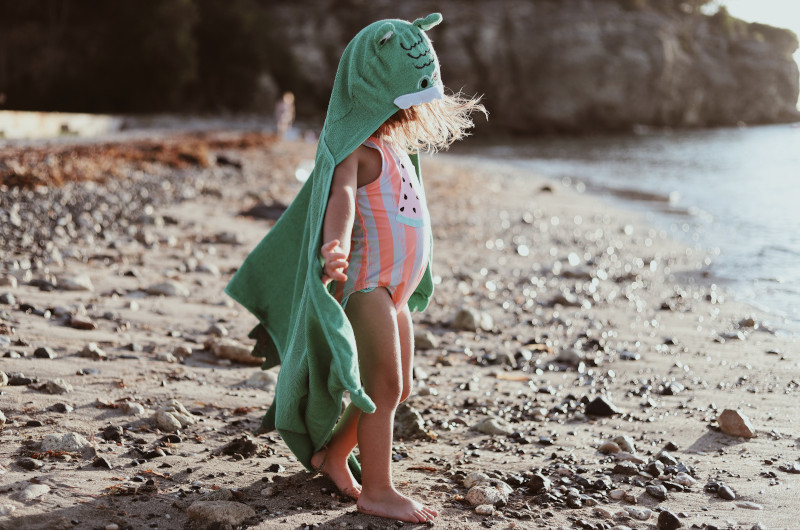 Kind mit Kapuzenponcho Kleines Kind mit Kapuzenponcho als Windschutz