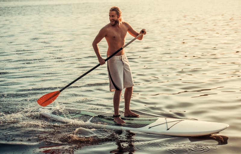 Mann steht auf einem aufblasbaren SUP Board