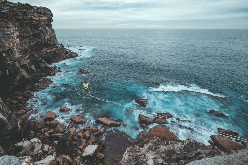 Eine Frau balanciert auf einer Slackline am Meer. Slackline balancieren am Meer.