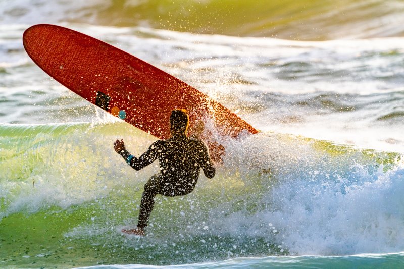 Surfer wird von einer Welle vom Surfboard geworfen.