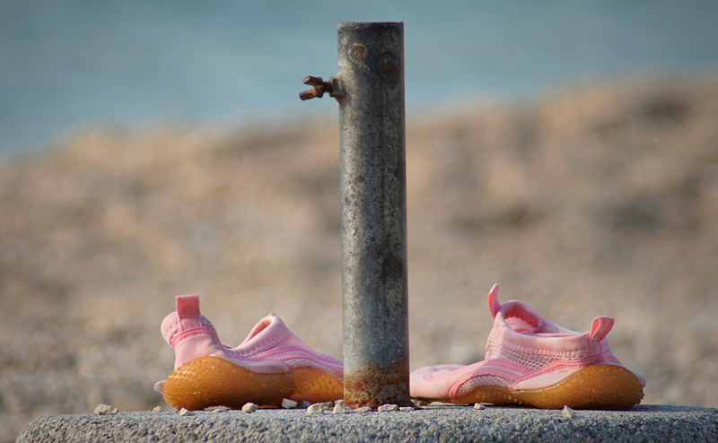 Ein paar Aquaschuhe an einem Kiesstrand