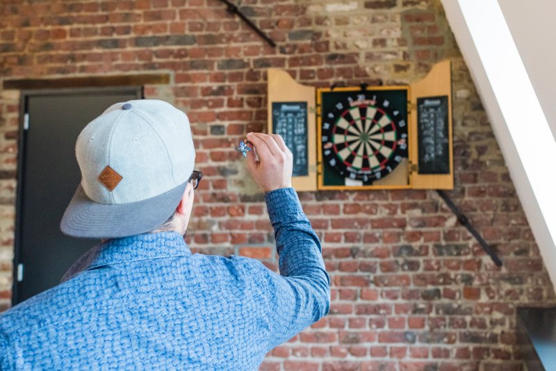 Dartspieler wirft auf Dartstaender an einer Wand