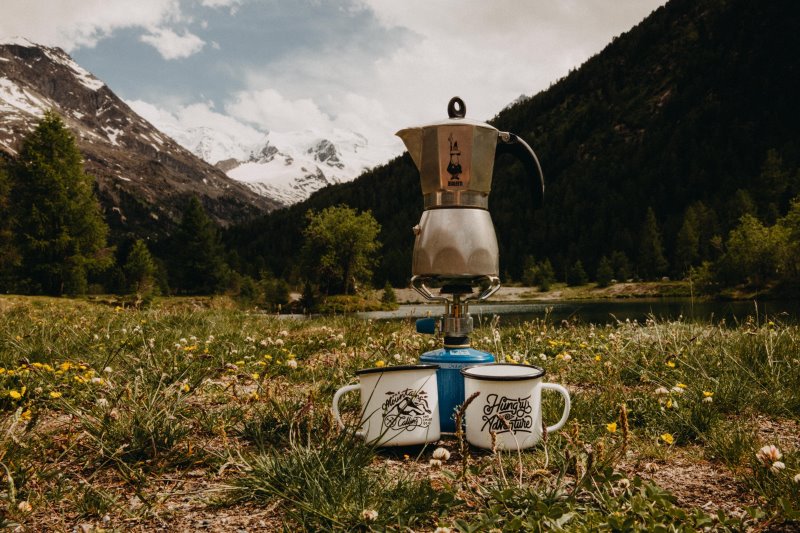 Kaffeekanne auf einem Gaskocher mit zwei Tassen in den Bergen