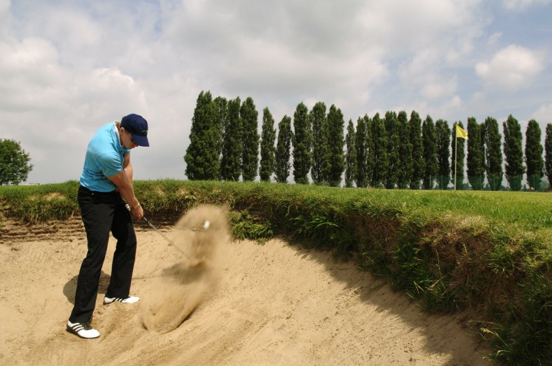 Golfschläger im Bunker Golfball wird mit dem Golfschläger aus dem Sand geschlagen