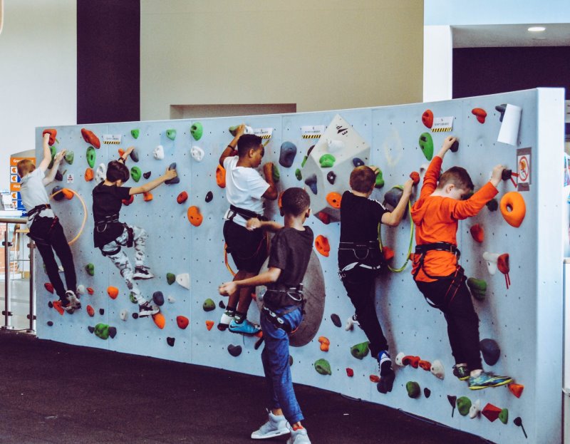 Mehrere Kinder klettern an einer Kletterwand. Kletterwand für Kinder
