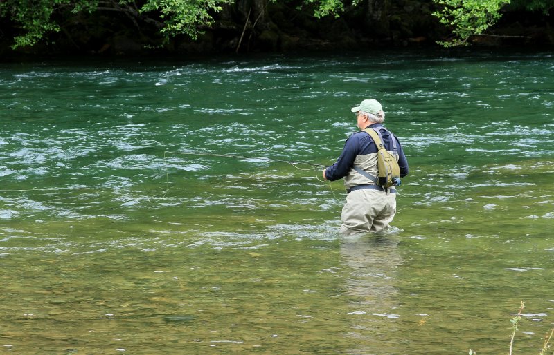 Ein Mann angelt mit einer Neopren Wathose im Fluss.