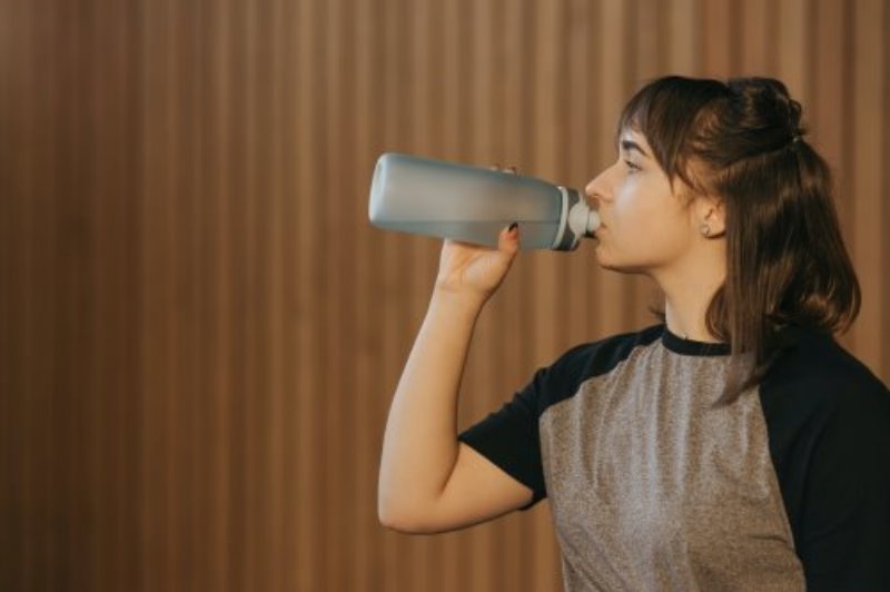 Eine Frau trinkt aus einer Trinkflasche. Wasser trinken