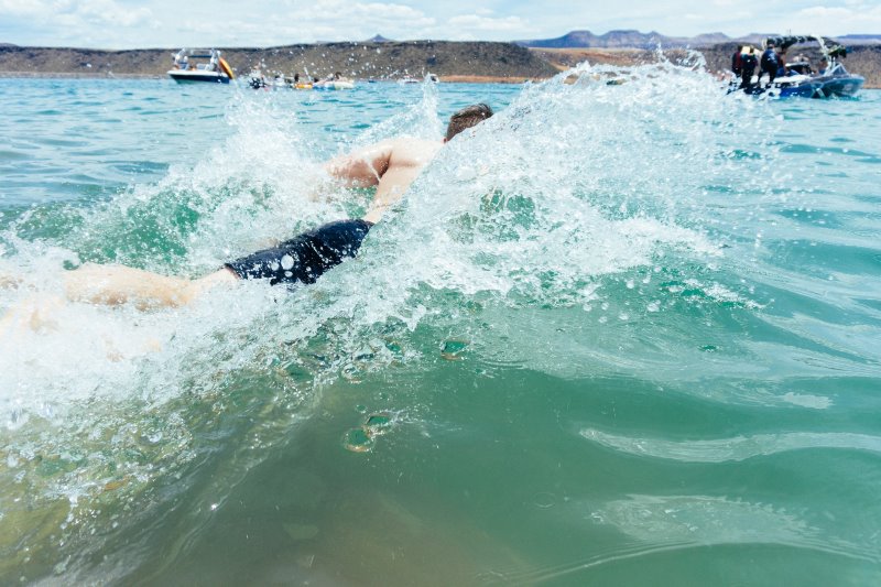 Schwimmen vom Schlauchboot mit Schlauchbootleiter Mann schwimmt energisch im Wasser vom Schlauchboot aus