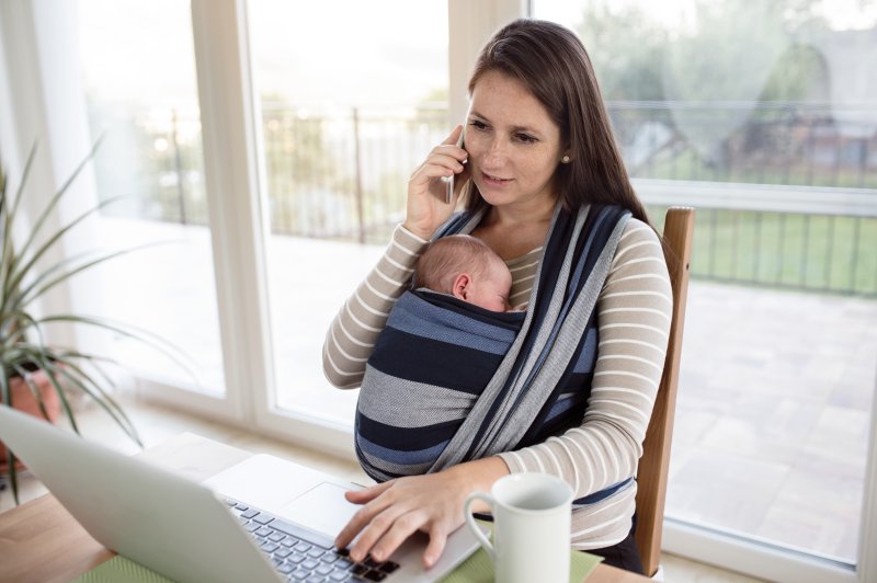 Ein Baby in einem Tragetuch während Mama arbeitet