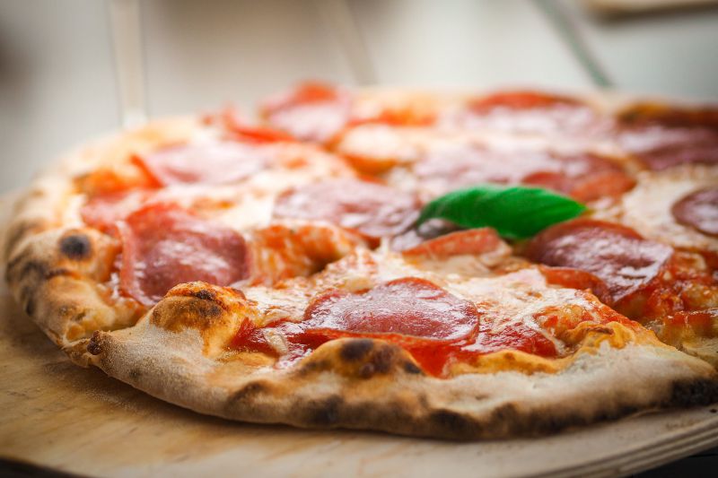 knusprige Pizza wie vom Italiener Die knusprige fertige Pizza liegt auf einem Holzbrett