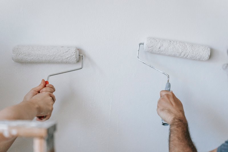Zwei Hände streichen eine Wand