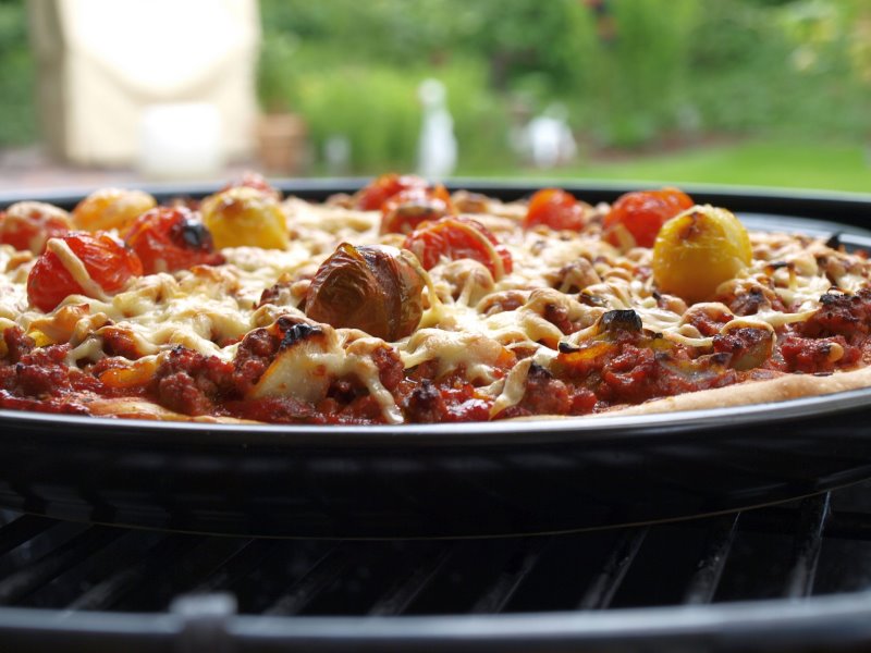 Pizza vom Grill auf einem Pizzastein Pizza vom Oberhitzegrill