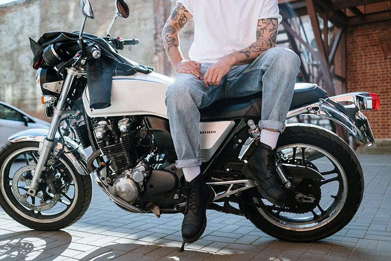 Tourenstiefel auf einem Motorrad Mann mit Stiefeln sitzt auf Motorrad