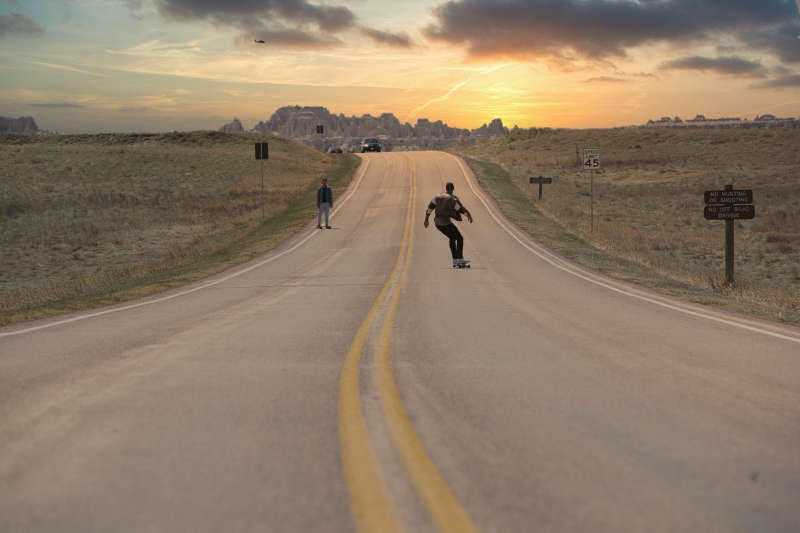 Downhill Longboard Junge skatet auf der Straße dem Sonnenuntergang entgegen
