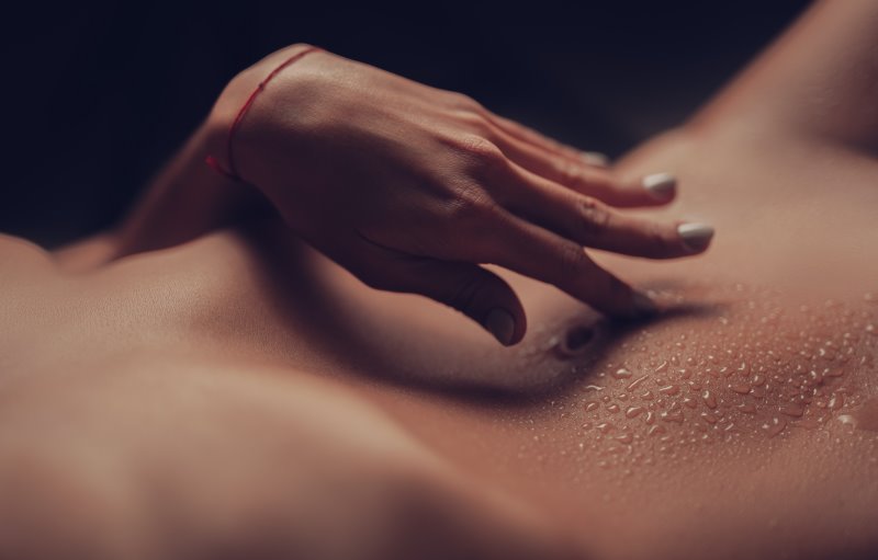 Frau streichelt sich an dem nassen Bauch entlang