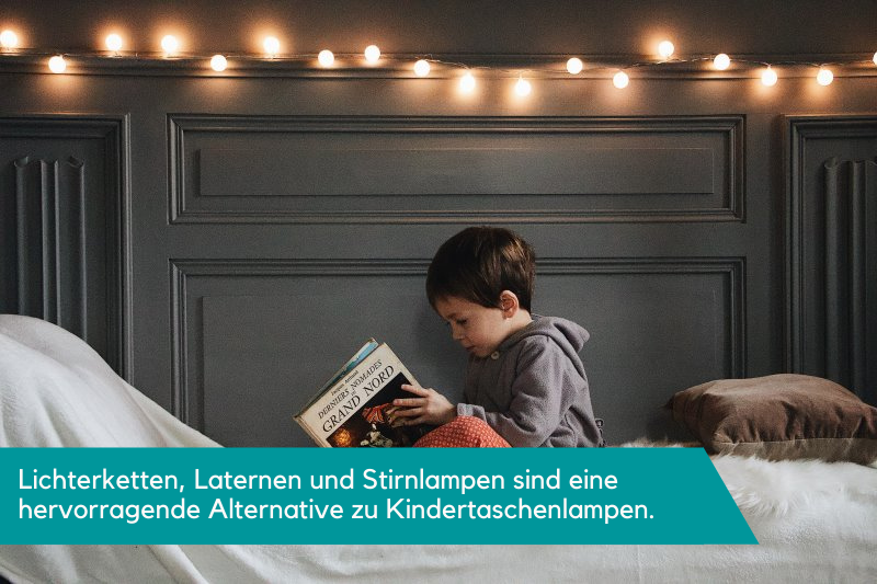 Ein Kind ließt unter einer Lichterkette ein Buch.