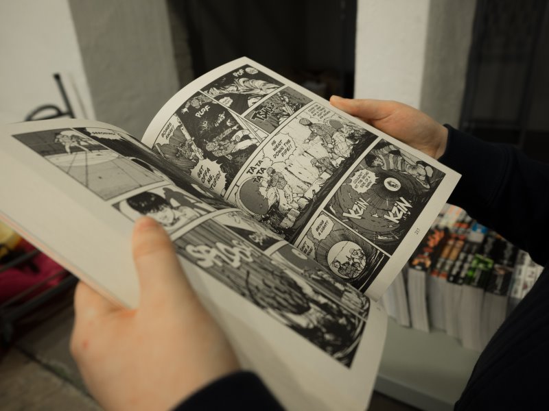 Hände halten einen aufgeschlagenen Manga