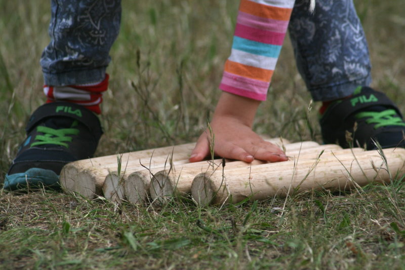 Kind legt eine Hand auf die 6 Wurfstäbe kind Wikingerschach Kubb