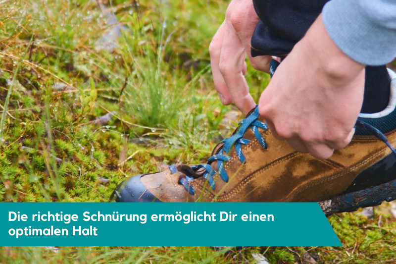 Braune Zustiegsschuhe mit blauen Schnürsenkel auf Wiese werden geschnürt.