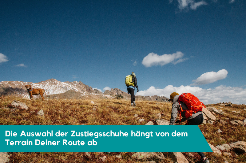 Zwei Wanderer mit Hund beim Anstieg zum Felsen.